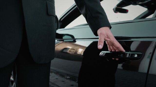 man in pak opent de deur van een taxi